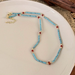 Detail of beaded turquoise necklace with gold clasp on vintage tray with newspaper