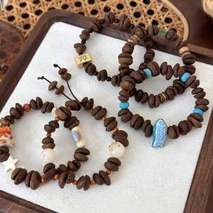Coffee bean beaded bracelet with cat claw charms and mahjong tile detail on tray