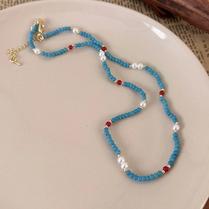 Detailed view of handmade beaded necklace with pearls on a vintage ceramic plate