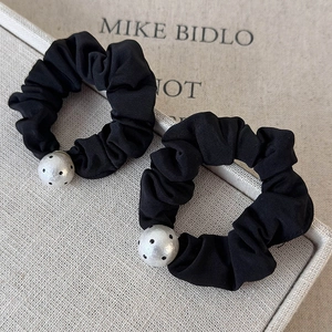 Detailed view of black polka dot cotton scrunchies with white decorative beads