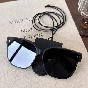 Detail of black faux leather eyewear pouch and long lanyard with stylish square sunglasses