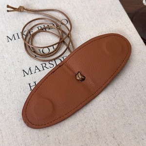 Detail of brown litchi pattern leather hat clip with fine stitching and woven lanyard