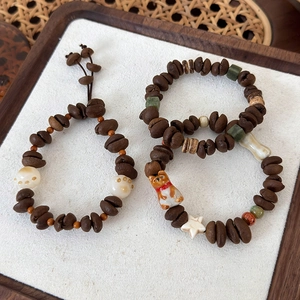 Detail of coffee bean bracelet with ceramic puppy and white cat paw beads on wooden tray
