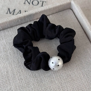 Detailed view of black pleated hair scrunchie with a white polka dot bead accessory