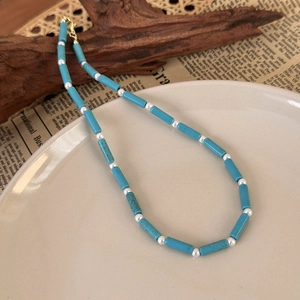 Retro beaded necklace with blue turquoise cylinders and white pearls on a ceramic plate