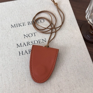 Detail of a brown lychee pattern leather hat clip and cloche style bag pendant charm