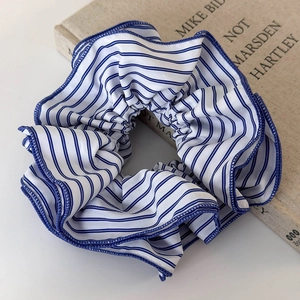 Détail d'un chouchou en tissu rayé bleu et blanc avec bords ondulés en surjet soigné