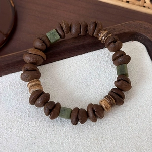 Macro detail of coffee bean cat claw beaded bracelet with green jade and wooden accents