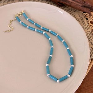 Detail showing blue turquoise-style columns and white pearls on a beaded necklace chain