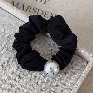 Detailed shot of black pleated silk hair scrunchie with a vintage polka dot bead accent