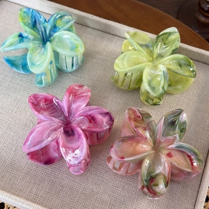 Dettaglio di pinze per capelli a forma di fiore con trama marmorizzata colorata su vassoio