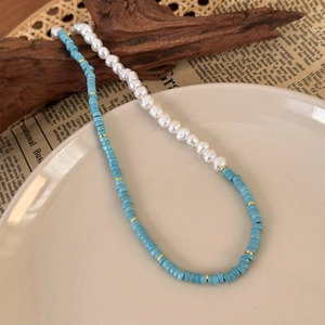 Detail of split design necklace with white pearls, teal beads and gold metal accents