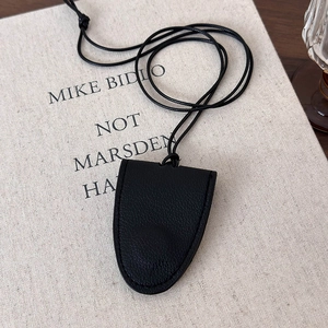 Detail of black leather bell-shaped charm with precise stitching and lychee texture