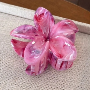 Dettaglio molletta per capelli a fiore in acetato marmorizzato rosa su vassoio