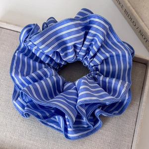 Détail macro du chouchou en tissu rayé bleu avec texture sur fond gris élégant