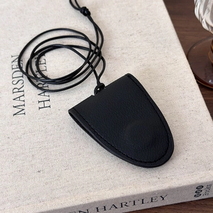 Detail of black lychee leather key cover pouch with long neck lanyard on a book