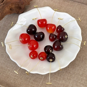 Flat lay of red and purple cherry earrings in a shell-shaped dish on burlap cloth