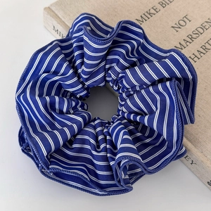Gros plan d'un chouchou en tissu à rayures bleues et blanches avec plis texturés