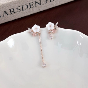 Detail of asymmetric 925 silver needle shell flower earrings with dangling zircon