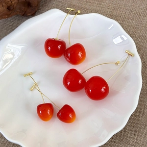 Three pairs of cherry-shaped earrings with translucent red resin and gold metal details