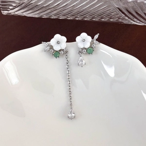 Detail of asymmetric shell flower earrings with green gems and silver dangling chains