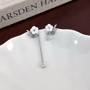 Detailed view of asymmetric 925 silver flower earrings with shells and green gems