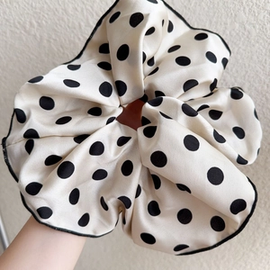 Detailed shot of large cream polka dot scrunchie with elegant black silk piping texture