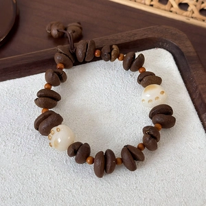 Detailed view of coffee bean beads and cat paw charms on a creative beaded bracelet