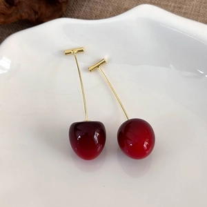 Detail of red cherry drop earring with translucent resin fruit and gold metal stems