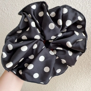 Close-up of a large black and white polka dot scrunchie with silky fabric texture