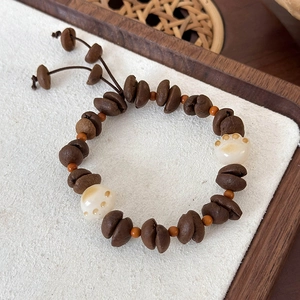 Close-up of coffee bean beads and cat paw charms on a handcrafted elastic bracelet