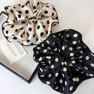 Detail of elegant polka dot large scrunchies in black and beige satin fabric