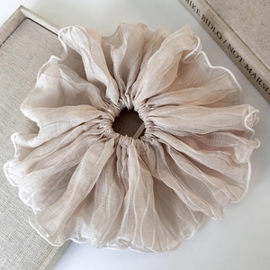 Detail of elegant beige pleated oversized hair scrunchie with white scalloped edge finish