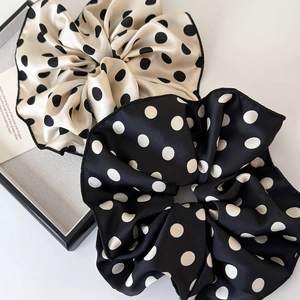 Detail of satin polka dot scrunchies in beige and black with soft glossy texture
