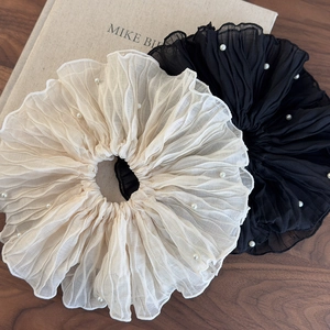 Detail of elegant pleated scrunchies in cream and black with delicate white pearl accents