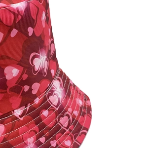 Gros plan sur le motif cœur rose et les coutures blanches du bord du chapeau