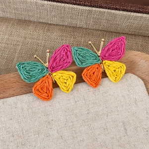 Detailed macro view of colorful raffia woven butterfly earrings with golden metal details