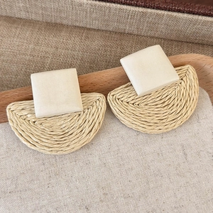 Detail showing bohemian woven raffia earrings with square top on a linen texture tray