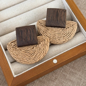 Detail of bohemian woven raffia earrings with dark wood square tops in a display box