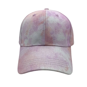 Detail view of tie-dye baseball cap with pink and purple glitter fabric and curved brim
