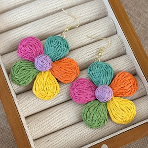 Close-up of colorful raffia flower earrings in a wooden jewelry display box