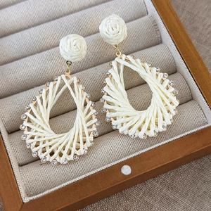 Close-up of woven rose stud earrings with rhinestone droplet frames in jewelry box