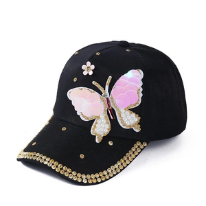 Black baseball cap featuring a large sequined butterfly and white pearl embellishments