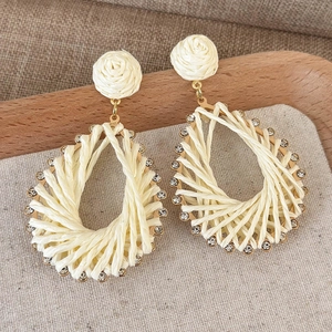 Close-up of handmade woven teardrop earrings with crystals and rose knot detail