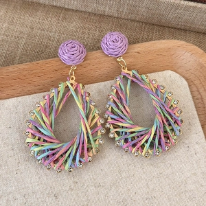 Detailed macro view of woven bohemian teardrop earrings with colorful rope and rhinestones