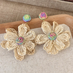 Detailed view of handmade woven raffia sunflower earrings with colorful fiber accents