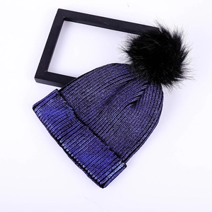 Women's winter thick knit beanie with gold-flecked blue yarn and faux fur pom-pom detail