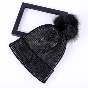 Chic black ribbed knit beanie featuring a fluffy pom-pom for winter warmth and style