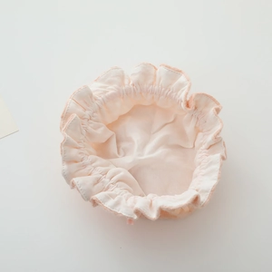 Détail du bonnet de naissance en dentelle rose pour bébé avec bords à volants