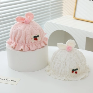 Détail du bonnet en dentelle pour bébé avec oreilles de lapin et nœud de cerise